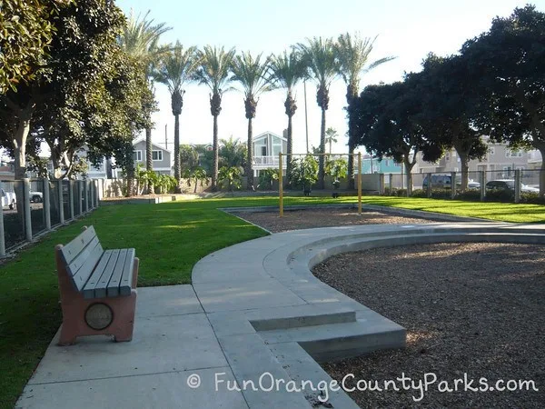 baby swings near grassy area and bench on concrete pad