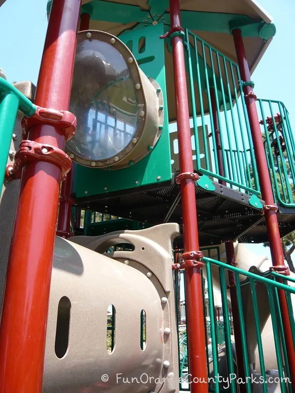green and rust colored playground with up-close view of 2 story play structure at Pines Park 