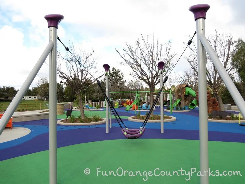 zip track swing in foreground with full playground in the background
