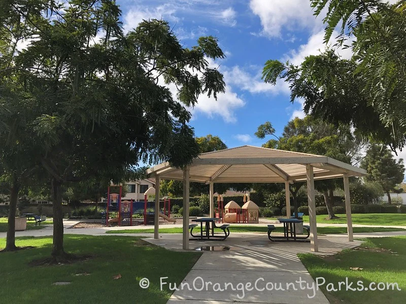 Ocean Breeze Park gazebo in a lush green area with trees and blue sky above.