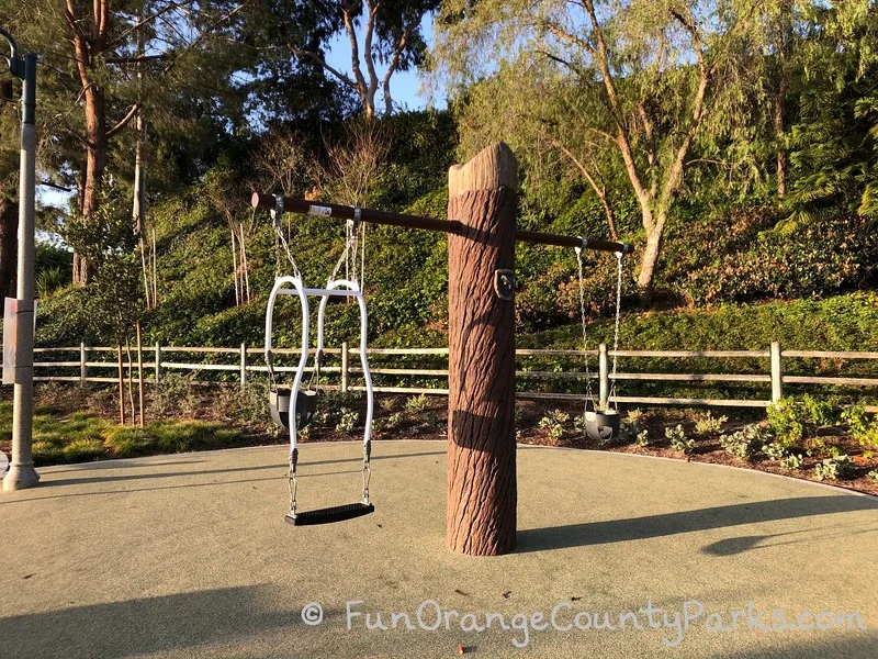 baby swings hung from a tree trunk post