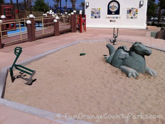 sand area with sea monster sculpture and digger at Courtney's Sandcastle Accessible Playground San Clemente 