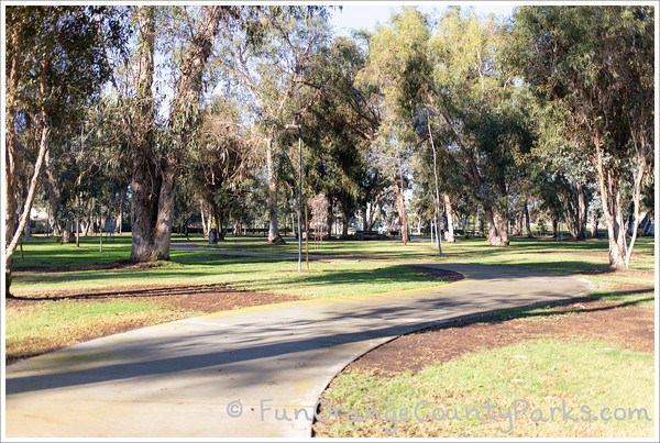 wide view of sidewalk into the grove of trees at Gibbs Butterfly Park in Huntington Beach
