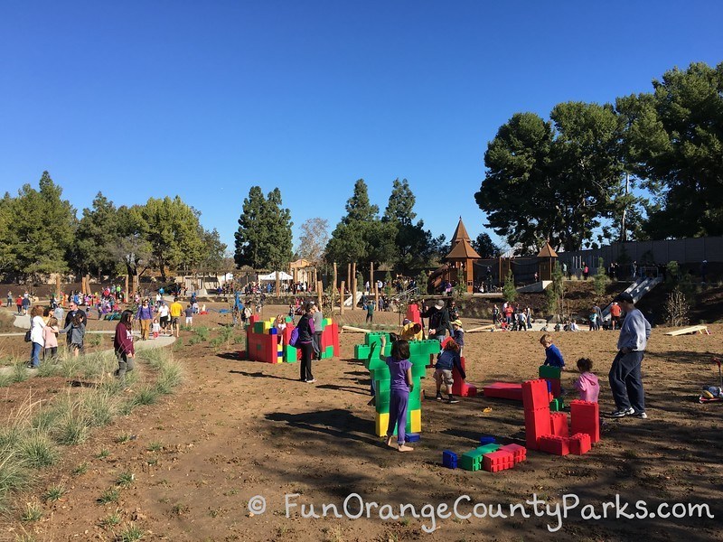 children playing with colorful large size LEGO bricks on open dirt field