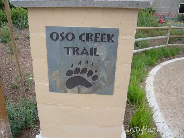 oso creek trail sign with bear print on concrete column