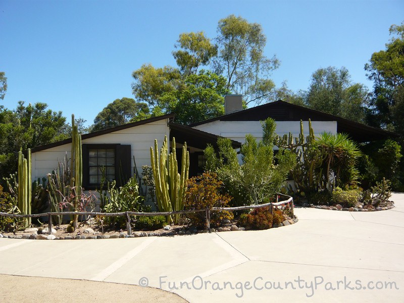 serrano adobe building - white building with cactus planted in front along a sidewalk