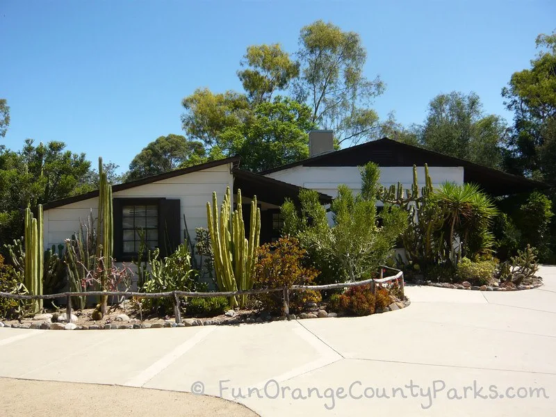 serrano adobe building - white building with cactus planted in front along a sidewalk