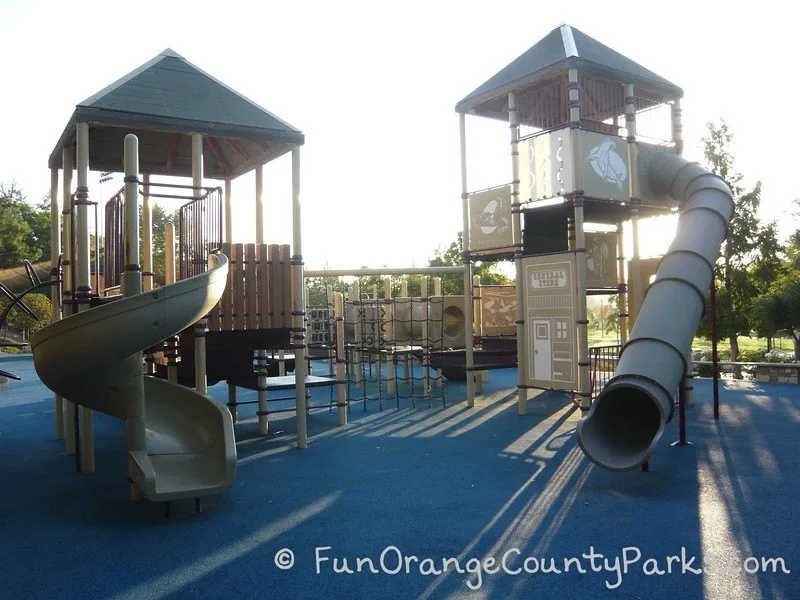 Tunnel slide and twisty slide backlit by sunrise at Laguna Hills Dino Park