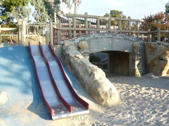 Dino Park in Laguna Hills view of metal slides and tunnel with fossils