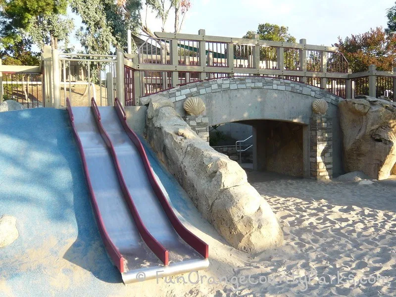 Dino Park in Laguna Hills view of metal slides and tunnel with fossils