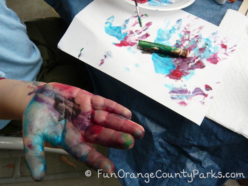 Child's hands while painting in blue and red paint