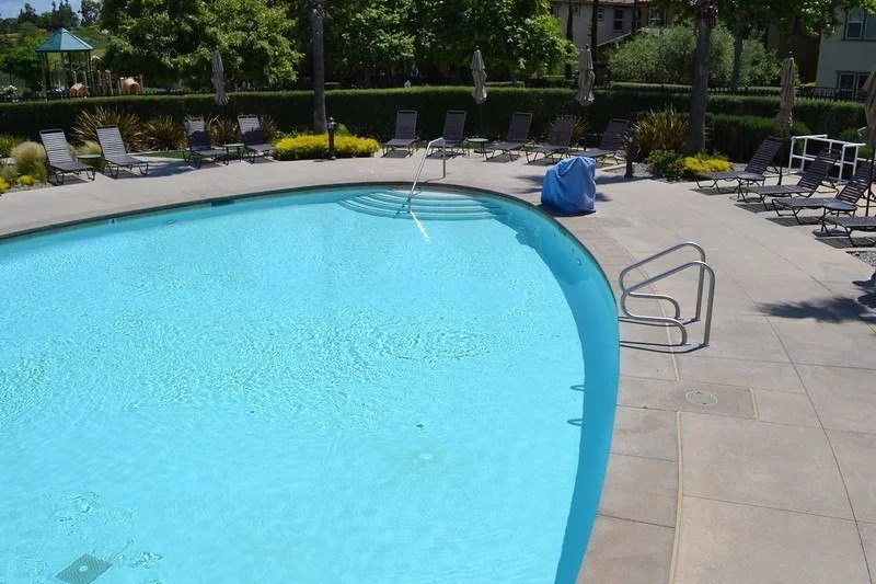 half of an oval-shaped pool with brown lounge chairs at the Aliso Viejo Aquatic Center