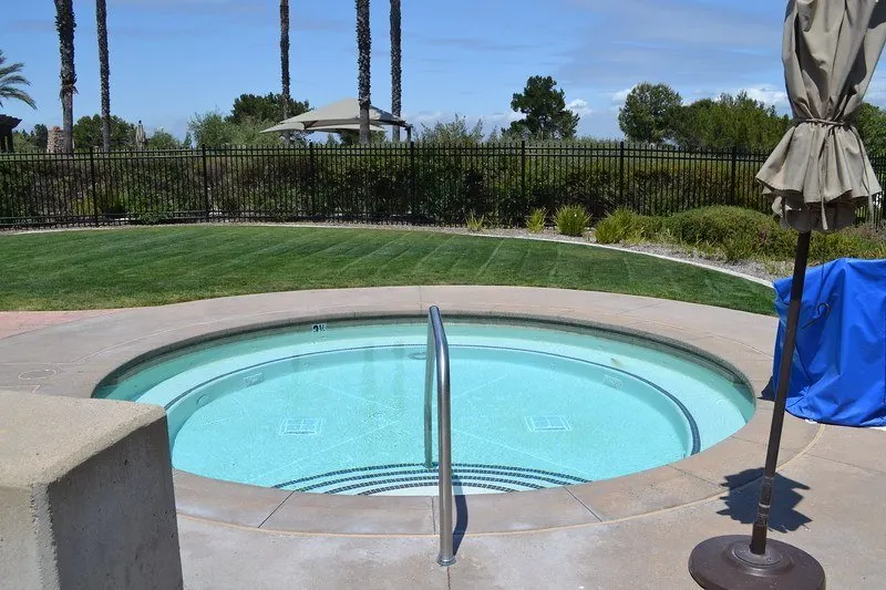 round concrete in-ground spa with lawn area nearby