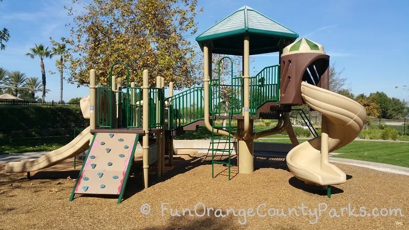 another view of the same playground where you can see a twisty slide and climbing board with grips