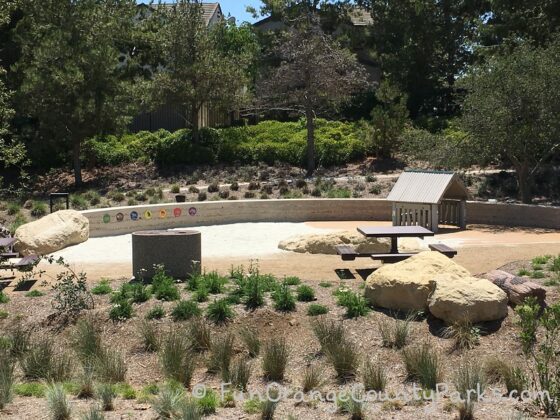 picnic table and native plants surrounding sand play area