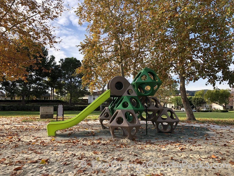 westridge park aliso viejo geometric climber with neon green slide on a sand play surface with fallen sycamore leaves