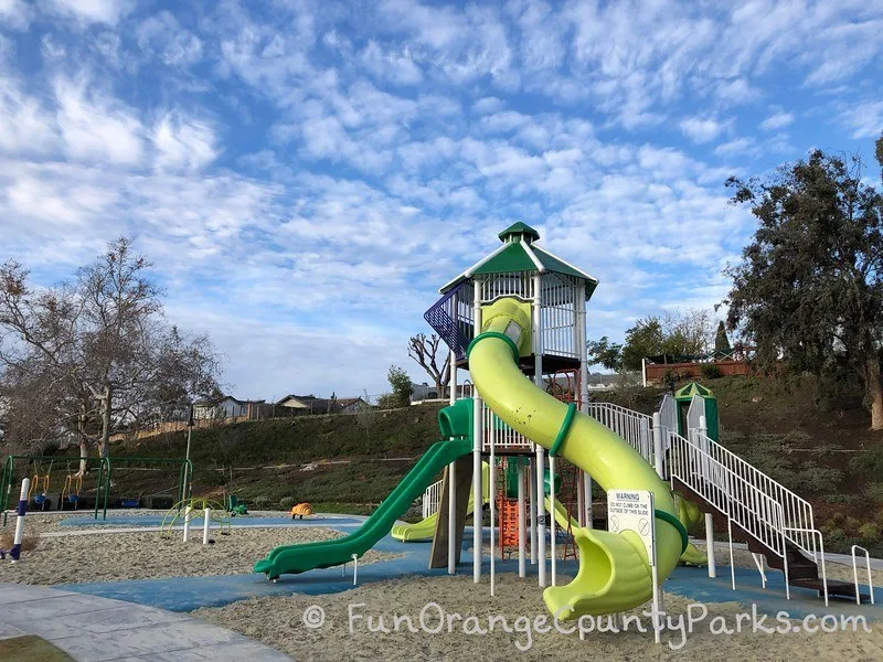 el dorado park mission viejo tall tunnel slide with distant view of the rest of the playground