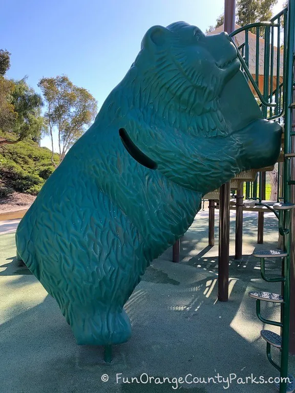 bear climber in green plastic that looks like a giant bear is leaning on the playground equipment -- with a way to climb up inside