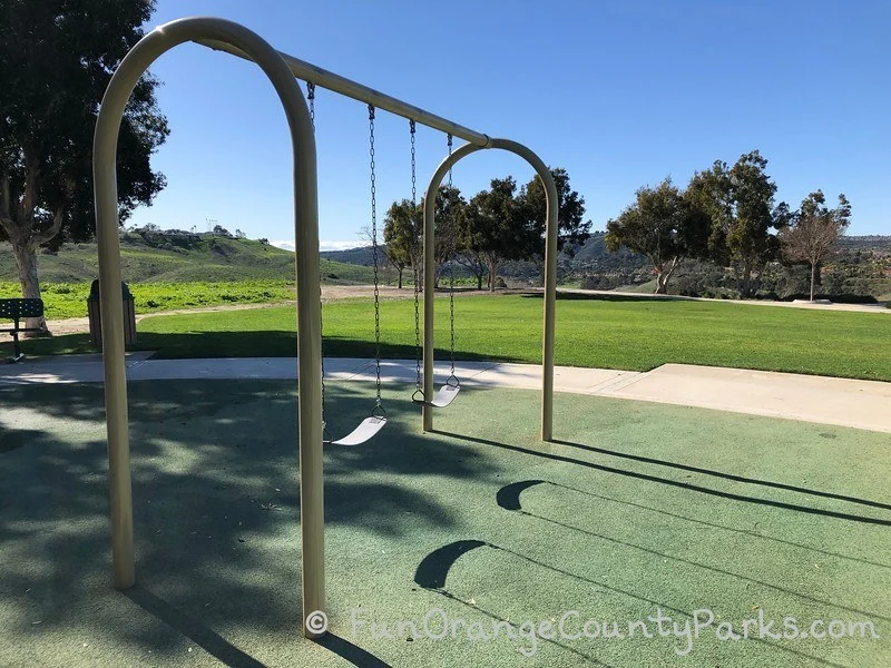 bench swings over a recycled rubber surface near a grassy area