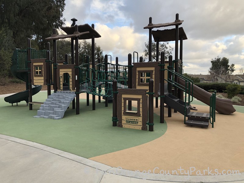 playground structure with slides, rock climbers, and a ranger station window
