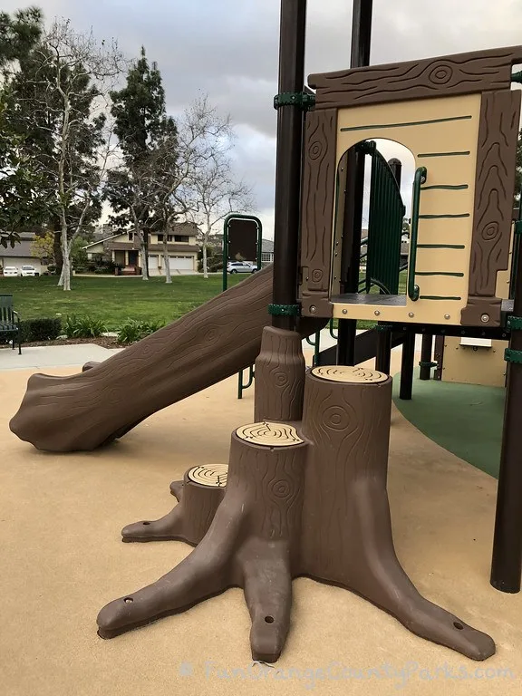 tree log steps and log slide at playground with background view of grass

