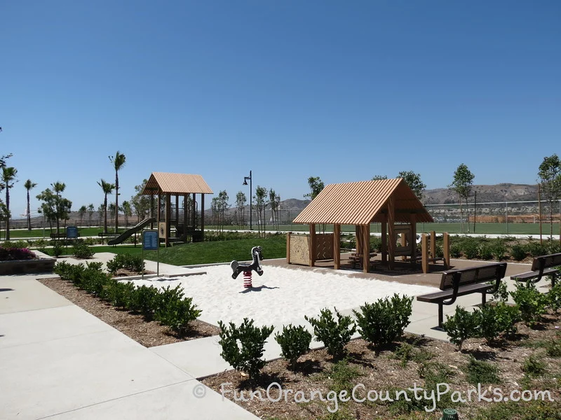 toddler playground at Baker Ranch Community Park in Lake Forest with sand under a spring ride-on horse with other play equipment that looks like little houses