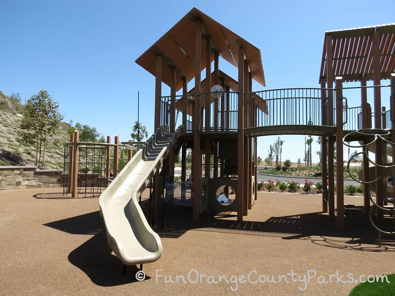 View of the monkey bars at Baker Ranch Community Park with a crooked slide  and climbing apparatus