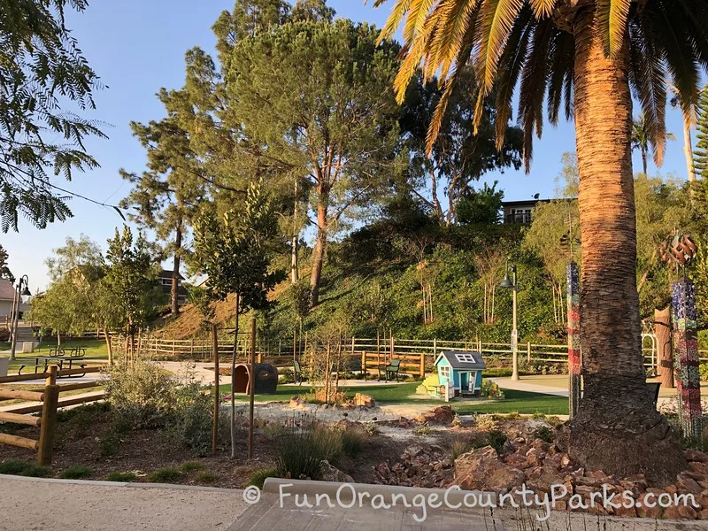 small blue clubhouse and tree tunnel on turf under a palm tree near a sandbox