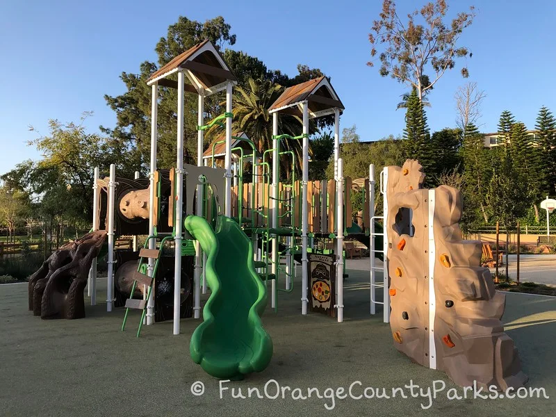 main playground with green slide and a climbing wall