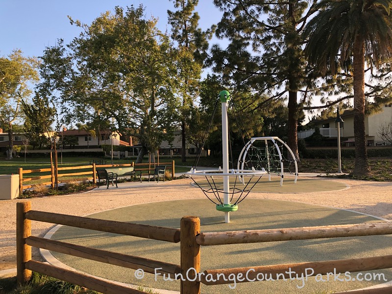 spinner and climber on recycled rubber pads at the back of the park surrounded by shade trees