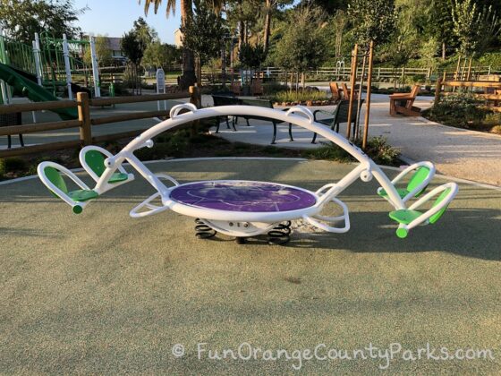 4 person teeter totter with neon green seats and a purple pad in the center