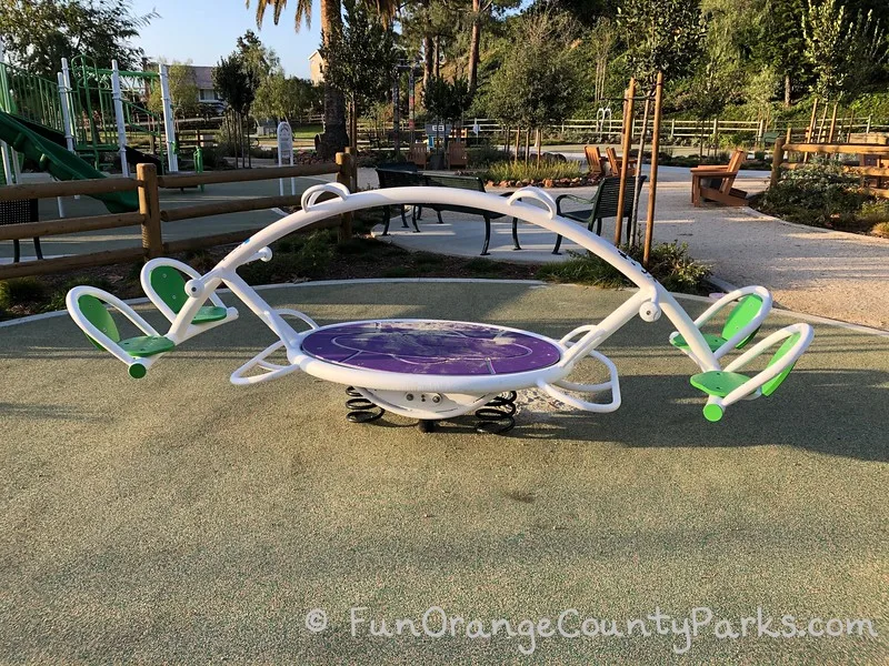 4 person teeter totter with neon green seats and a purple pad in the center