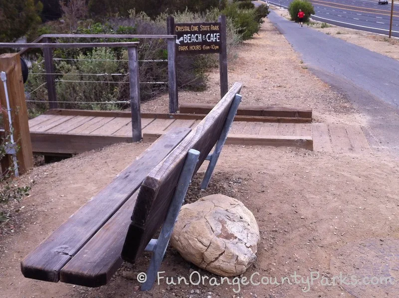 wooden bench near paved bike trail and steps down to Crystal Cove State Park