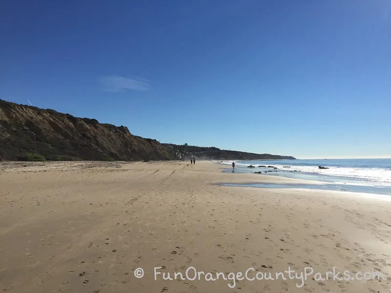 wide beach at Crystal Cove State Park which is almost empty except for a few people walking