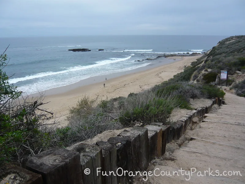 shoreline with obvious tidepools on a cloudy day with a wooden staircase leading down to the beach at Crystal Cove State Park