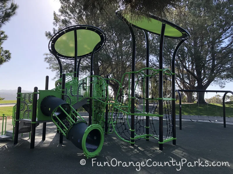 another view of the playground with 2 bench swings visible and close up of climbing area which has black netting for vertical and horizontal movement