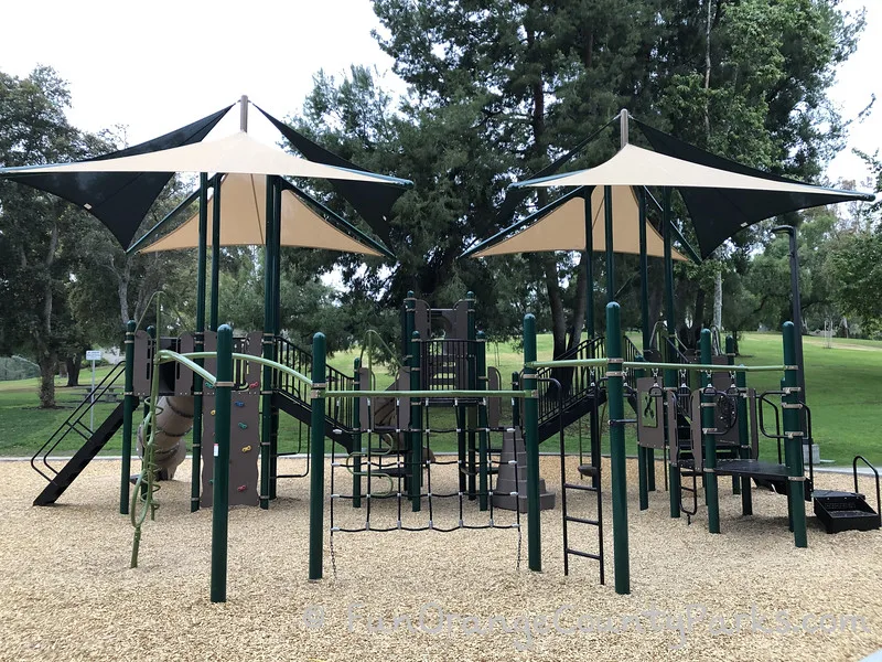 Rope climber and spinner with a climbing ramp and stairs visible against a lawn covered hill