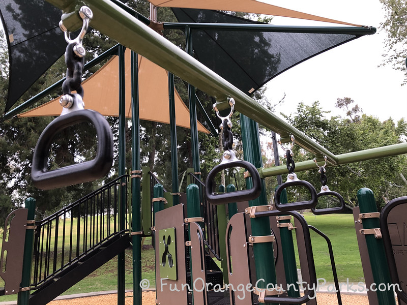 rolling hills park playground monkey bar handles framed against the playground equipment