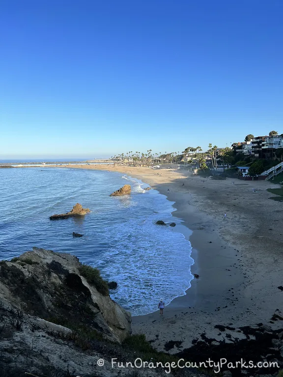 early morning beach view with rocks and light waves - half the beach is in the sun and the rest in the shade