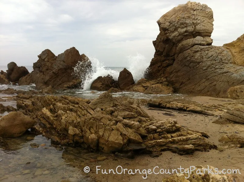 craggy rocks at the beach with a wave crashing over